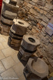 <center>Cordes-sur-ciel. Musée Charles Portal.</center>Les mesures en pierre de Cordes.
Avant 1’instauration du système métrique, les unités de mesure étaient d’une diversité et d’une complexité inextricables. Variant d'une localité à l'autre, elles faisaient l'objet d'une importante réglementation, d'une constante surveillance, et des mesures étalons étaient nécessaires. Il devait en exister à Cordes depuis la création de la ville, puisque la charte de fondation de 1222 stipule que le délit de faux poids ou fausse mesure sera puni d'une amende de 5 sous.
Tandis que les mesures de capacité pour l'huile et le vin étaient déposées aux archives de la maison de ville, celle utilisées pour les grains, plus volumineuses, étaient en pierre et abritées sous la Halle (ou place couverte). En 1467, lorsqu'est passé un bail pour l'étalonnage et le marquage (fleur de lys et château) des mesures la ville conformément aux escandils (étalons), elles sont au nombre de quatre, et représentent l’émine, la demi-émine, la quarte et la demi- quarte (ordre décroissant). Elles sont cerclées de fer et posées sur un socle pour être surélevées. A leur base s'ouvre le volet d’une trappe d'évacuation en fer, qui permet de faire glisser les céréales dans le récipient ou le sac.