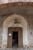 <center>Monestiès. L'église Saint-Pierre.</center>Le portail en arc brisé à bandeau sculpté est supporté par deux consoles ornées symboliquement d'un ange et d'un démon. Au tympan a été placé le buste d'une sainte femme provenant sans doute du château de Combéfa.