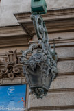 <center>L’opéra de Nice.</center>Sur les murs on peut voir de grandes lanternes en bronze richement ornée, suspendues à un bras d’applique en crosse (accolées à un support ornementé d’une lyre). Le luminaire est aujourd’hui électrifié, vitrée sur ses 4 faces.