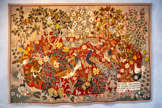 <center>Le musée Dom Robert et de la tapisserie du XXe siècle</center>Summertime
D'après DOM ROBERT (1907-1997)
Tapisserie de basse lisse, Exemplaire n° 5 Laine et coton
Atelier Tabard, Aubusson, 1943 Carton de 1941, 218,5 x 318 cm.< br> Jean Lurçat rencontre Dom Robert à En Calcat en septembre 1941 et lui conseille de choisir l’aquarelle La Ferme de Palaja comme maquette de sa première tapisserie. Le premier exemplaire est tissé dans les ateliers Tabard à Aubusson fin 1941. La palette proposée est assez retenue : fond vert-bleu et masse importante d’un rouge profond sur lesquels se détachent les blancs et les jaunes. La bordure rouge et l’inscription dans le cartouche en bas à droite relient cette œuvre à l’enluminure et à la tapisserie médiévale. Le texte est la clé de lecture de l’œuvre de Dom Robert : « Or je vous dis que Salomon lui-même dans toute sa gloire n’a pas été vêtu comme l’un d’eux » (Mt 6, 29) : la nature, dans sa magnificence, est inégalable. La tapisserie comporte les grands thèmes que Dom Robert déclinera par la suite : les animaux de basse-cour, les arbres, les fleurs et les papillons. La forme ovoïde contenant la scène centrale va devenir une des caractéristiques de ses compositions.