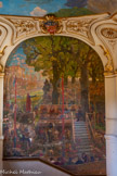 <center>Le Capitole.</center>« La fête des Jeux floraux » de Jean-Paul Laurens (1838-1921). Arnaud Vidal, le vainqueur de cette première joute poétique, debout sur une estrade, déclame ses vers devant les 7 troubadours créateurs du concours. Des tribunes débordant de spectateurs ont été installées dans le verger des Augustines, dont le couvent se situait hors la ville comme le dévoile la présence des hauts murs de l’enceinte. Sur la première volée de marches, les deux panneaux latéraux, de format réduit, servent d'introduction à la peinture principale.
