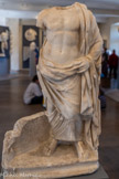 <center>Musée Saint-Raymond</center>Esculape.
Marbre d'Afyon (Turquie)
IIe siècle ? Esculape (Asclépios en Grèce) est le dieu de la médecine. Très jeune, son père Apollon le confie au centaure Chiron qui lui apprend l'art de la guérison. Un serpent, dont la queue est visible en bas à gauche, nous permet de le reconnaître. Il s'agit ici d'une excellente réplique d'époque romaine d'un original grec du Ve siècle avant notre ère.