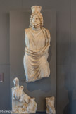 <center>Musée Saint-Raymond</center>Sarapis-Pluton
Marbre blanc
IIIe-IVe siècle. <br>
Le dieu Osiris-Apis devient Sarapis avec les Grecs installés en Égypte. Il avait pour épouse Isis. Vénéré pour ses capacités de guérison, il est ici assimilé à Pluton (l'Hadès des Grecs), dieu des forces souterraines. Ceci explique la présence de Cerbère, chien à trois têtes, gardien du royaume des morts (les Enfers).
Il est coiffé de la couronne blanche de la Haute-Égypte, portée par les pharaons, et d'un récipient (modius) servant d'unité de mesure pour le grain, symbole d'abondance des récoltes.