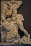 <center>Musée Saint-Raymond</center>Hercule et les bœufs de Géryon. Dixième des douze travaux. Híspame.
Géryon était un géant à trois têtes qui possédait un immense troupeau de bœufs. Eurysthée ordonna à Hercule (l'Héraclès grec) de lui ramener ce troupeau. Lorsque le géant accourut pour défendre ses bêtes, Hercule le tua.
Ce relief représente l'agonie du géant qui, revêtu d'une cuirasse identique à celle des généraux romains, un genou à terre, agonise. Observez de près ses trois têtes : l'une est déjà morte (elle repose sur son épaule) ; la deuxième rend l'âme (elle s'affaisse sur le côté) ; Hercule s'apprête à frapper la dernière.
Ce relief est le plus grand de tous. On pourrait y voir une allusion aux victoires militaires de l'empereur Maximien Hercule en Espagne. A cette occasion, peut-être a-t-il séjourné à Chiragan, ce qui expliquerait la conception de tout le grand décor sculpté présenté dans cette section.
