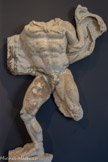 <center>Musée Saint-Raymond</center>Hercule et Cerbère. Douzième des douze travaux. Enfers.
Hercule (l'Héraclès grec) dut ramener vivant Cerbère. Ce chien à trois têtes était le gardien des Enfers : le monde des morts dont nul humain ne pouvait revenir.
Pluton (l'Hadès grec), le dieu de ce royaume infernal, autorisa Hercule à capturer Cerbère, à condition qu'il le fasse sans armes. Le héros empoigna le chien par le cou puis l'apporta à Eurysthée qui, terrifié, ordonna à Hercule de ramener ce monstre là où il l'avait trouvé.
Sur le relief, le mouvement de la léonté, qui flotte dans le dos d'Hercule, prouve la grande agitation de la scène. Cerbère était sans doute représenté à droite du héros.
Cette épreuve a été identifiée par comparaison avec des images, sur des sarcophages ou des mosaïques, qui illustraient ce thème.