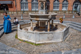 <center>La place Saint-Étienne</center>Trois marches permettent de descendre à la fontaine. Un premier bassin octogonal reçoit l'eau de la bouche de quatre mascarons à tête fantastique qui ornent la vasque supérieure portée par quatre colonnettes – la vasque originale venait de l'ancienne fontaine du cloître Saint-Étienne, les colonnettes de l'église Saint-Pierre-des-Cuisines. À l'intérieur des niches, des marmousets en bronze, fondus par Pierre Chevenet en 1593 et restaurés par Pierre Affre en 1649, rejettent l'eau par la gueule de poissons qu'ils tiennent dans leur main.