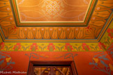 <center>Le château Laurens</center>Le petit vestibule. Le registre supérieur offre une frise de bucranes alternant avec un motif végétal. La tête du bovidé stylisée est de couleur verte et jaune, soulignée d’un contour rouge, des yeux rouges, tandis que la rosette placée entre les cornes est verte avec des détails rouges. Le bucrane entre les cornes duquel se trouve la rosette, – parfois assimilée à un disque solaire –, évoque la déesse Hathor, et revêt une signification apotropaïque.