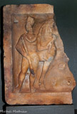 <center>Relief votif aux Dioscures</center>Marbre blanc. IIe siècle apr. J.-C.
 A l'origine, sans doute un ex-voto. Placage figurant un Dioscure debout à côté de son cheval, qu'il tient de la main gauche par la bride ; la main droite enserre une lance. Vêtu d'une chlamyde, le personnage porte le pilos (bonnet conique). Les Dioscures étaient les patrons de bateliers.