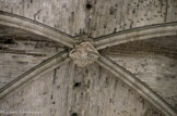 <center>Basilique de saint-Maximin.</center>Une clef de voûte avec un personnage à coiffure singulière flanqué d'un blason et d'un écusson.