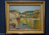 <center>Le Port de Cassis</center>CHARLES CAMOIN. Huile sur toile, 1901.
Le Port de Cassis, dont le premier propriétaire était le Docteur Reynolds qui avait soigné Van Gogh en 18E9 et reçu en dédommagement son portrait par l'artiste (Portrait du Dr Rey, Musée Pouchkine, Moscou), fut très probablement peint en 1901. Particulièrement lumineux, le tableau témoigne de la bonne connaissance qu'a déjà alors Camoin de la peinture impressionniste. La couleur est appliquée par petites touches dont la taille et les accents varient selon les éléments : la surface de l’eau est ainsi animée d'un entremêlement de touches jaunes, vertes, bleues et orangées alors que le ciel est composé de légers frottis d'un bleu lavé. L’accord orange/vert domine l'ensemble et restitue la clarté du port qui apparaît comme un gemme scintillant inscrit dans son écrin de montagnes. Le caractère très construit de la composition, qui s'articule à partir du dessin précis des quais et des bateaux, confère toutefois au tableau un aspect très classique dans sa facture.