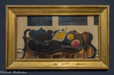 <center>Nature morte à la théière noire</center>GEORGES BRAQUE (1882-1963). Huile et sable sur toile, 1941-1942
Nature morte à la théière noire s'inscrit dans une période bien féconde où Braque, à travers des natures mortes plus austères, se tournera davantage vers des objets quotidiens de cette période d'Occupation. Une théière noire se détache sur un plateau dont la noirceur semble encore plus profonde et qui est posé sur une modeste table en bois. Les cernes du bois, réalisés avec le manche du pinceau, ressortent avec force, soulignent la modestie de la table et font allusion à la sécheresse des temps. Les fenêtres masquées en temps de guerre pour éviter de guider l'ennemi, marquent un désespoir face au monde extérieur ; il est peut-être aussi possible d'y voir deux cadres de tableau dont la noirceur pointerait l'angoisse pour un art qui subissait moins d'un an plus tôt l'autodafé des peintres 