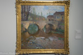 <center>Le pont sur le Vert</center>HENRI MARTIN, (1860-1943). Huile sur toile
En 1899, Henri Martin achète Marquayrol. Ce domaine lotois qui surplombe Labastide-du-Vert fut un ancrage méridional définitif. Dès lors, la maison, sa pergola, son jardin peuplé de cyprès qui rappellent l'Italie, le bassin circulaire, le village, son église, le Vert et les peupliers qui le bordent, son pont, furent des motifs favoris. Il multiplia avec amour leurs portraitures. Ils devinrent matière à décliner à l'envie des harmonies lumineuses et colorées variant au cours des heures et des saisons.
Comme à son habitude Henri Martin architecture, sans qu'il n'y paraisse, le sujet qui l'inspire. La touche dissociée variée très libre, virtuose sans systématisme, plaiderait pour une datation des années de maturité du peintre.