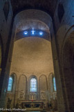 <center>Saint Guilhem le Désert. </center> L'abside de 12 m d'ouverture contraste avec la nef très étroite car on a voulu conserver la crypte située sous le chœur, lors de la reconstruction de l'abbaye au XIe siècle. Elle est voûtée en cul de four et la lumière entre par trois importantes baies en plein cintre. Sur les murs des arcades en plein cintre reposent sur des demi-colonnes engagées, décoration caractéristique du premier art roman. Entre l'abside et la nef il y a une travée voûtée en berceau et la différence de niveau entre les voûtes est compensée par un arc diaphragme sur lequel se trouvent trois ouvertures dont une cruciforme qui est placée entre deux oculi.