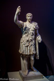 <center>Trajan.</center><center>Trajan.</center>C’est une statue reconstituée : les bras sont modernes, la tête de est celle de Trajan et la cuirasse est de son époque. Sous Trajan, l’empire a atteint ses frontières les plus étendues. Trajan est célèbre pour ses campagnes, en particulier contre les Daces. Tous les empereurs se sont fait représenter en chef des armées. Le portrait est assez réaliste, il ne ressemble pas à Auguste. Ce qui est le plus spectaculaire est la cuirasse. On y voit des motifs destinés à faire peur, d’autres pour montrer les conquêtes de l’empereur, des captifs enchaînés comme sur les arcs de la région, les victoires qui vont accrocher les boucliers autour d’un trophée et au-dessus, le duocéum qui est sensé diffuser dans tout le monde connu l’écho des victoires de l’empereur. Trajan a adopté sur son lit de mort Hadrien, par la volonté de son épouse Clotilde qui voulait que ce soit lui qui lui succède.