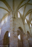 <center>Abbaye de Noirlac. </center> L'église abbatiale. Conformément à l'esprit de Cîteaux, tout décor sculpté est banni : les chapiteaux sont nus et les vitraux uniformément gris.