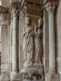 <center></center><center>Romans-sur-Isère. </center> Collégiale Saint-Barnard. Sculptures du portail. A gauche, saint Pierre au nord, identifié par son nom « SCS (P)ETRUS » sur le phylactère qu’il déroule. Ces statues, avec leur léger fléchissement des jambes, la finesse et le drapé des vêtements s’apparentent aux sculptures provençales d’Arles et de Saint-Gilles-du-Gard. Les chapiteaux des colonnettes sont surmontés de motifs de palmettes disposés en frise au-dessus de l’abaque. Ils sont historiés : le Christ et les pèlerins d’Emmaüs (à noter les sacoches en bandoulière),