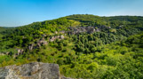 <center>Conques</center>Vue générale depuis le site du Bancarel. À l'intérieur d'un plateau ondulé composé de schistes ou de granits, les rivières du Lot, du Dourdou et leurs affluents ont ouvert un réseau de vallées sinueuses et profondes, formant le Ségala de Conques. Ici, les gorges creusées par le torrent de l'Ouche, sur le point de rejoindre la vallée perpendiculaire du Dourdou, s'élargissent quelque peu et tracent une sorte de cirque dont la concavité - la « conque » - vient échancrer le plateau aux horizons tabulaires. Il s'agit d'un véritable relief en creux. Pentes escarpées, affleurements de rochers et taches sombres des châtaigneraies engendrent un paysage à la fois austère et grandiose.