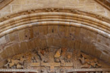 <center>L'église abbatiale Sainte-Foy</center>Dans les écoinçons, deux anges sonneurs de cor (ou d'olifant), les ailes déployées et les jambes tournoyantes « coudées en svastika », annoncent le retour du Christ aux quatre coins du monde. Des anges, curieux, sont sculptés sur l'archivolte. Ils pointent leur nez au-dessus du bandeau et, avec leurs mains, roulent le tapis du firmament.