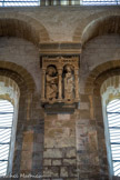 <center>L'église abbatiale Sainte-Foy</center>Triptyque de l'Annonciation. Les statues de l'Archange Gabriel et de la Vierge sont abritées sous deux arcades retombant sur trois colonnettes munies de chapiteaux à feuilles d'acanthe. L'archange Gabriel, nimbé, s'avance vers la Vierge, la main tendue. Marie a la main grande ouverte sur la poitrine se disant servante du Seigneur. De la main gauche, elle se débarrasse de sa quenouille ; elle la tend à sa servante qui tient déjà une pelote de laine ; cette servante, de plus petite taille que la Vierge, se trouve en arrière sur le côté latéral, séparée elle aussi de la Vierge par une colonnette.