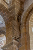 <center>L'église abbatiale Sainte-Foy</center>De part et d'autre de ce groupe de l'Annonciation deux personnages sont présents : l'un est Isaïe porteur d'une tige fleurie, évocation de l'arbre de Jessé ; il tient déroulé un phylactère. Il porte une longue barbe ; il est revêtu d'une robe, d'une dalmatique et d'une chasuble.