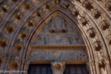 <center>La cathédrale Notre-Dame de Rodez</center>Malgré les destructions révolutionnaires, les vestiges de sculpture du
tympan permettent encore de deviner les contours d’un Couronnement de la
Vierge : la Vierge et le Christ sont assis sur un très beau banc ouvragé, encadré
par deux anges. Un autre ange volant au-dessus d’eux dans un ciel étoilé porte la
couronne destinée à la Vierge. Les dais surmontant les deux protagonistes et ceux
qui séparent les anges des voussures du portail sont autant de petites architectures
gothiques miniatures dont la finesse ne peut que faire regretter davantage la
destruction quasi complète des personnages à la Révolution.