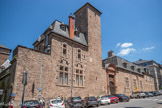 <center>Le palais Episcopal </center>Palais Episcopal propriété du Conseil Départemental de l'Aveyron.
Le palais Episcopal occupe ce site depuis le XV° siècle. Il fut d'abord édifié entre la cathédrale et la «tour Corbières» (1445) par Mgr Bertrand de Chalençon.
Ce premier palais s'appuie sur le rempart, en lien direct avec la cathédrale par la porte Saint Martial (démolie au XIXe siècle).
En 1515 Mgr François d'Estaing l'agrandit en construisant la haute « tour carré ». Son successeur, le Cardinal Georges d'Armagnac, engage la construction des arcades «renaissances» soutenant la grande terrasse. C'est Mgr Jacques de Corneilhan qui finira ces travaux: En 1589 le palais est détruit par les Ruthénois durant la guerre civile.