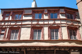 <center>Rodez</center>La Maison Trouillet date du XVe siècle. Ancienne maison qui appartenait à une famille d'importants marchands. Les formes architecturales et le
décor de sa façade principale,
rue du Bal, témoignent de son
édification dans la seconde
moitié du xv e siècle. L’édifice
appartenait alors à la famille
Gauch. Comme d’autres
propriétaires de grandes
demeures vers la place de
l’Olmet, on peut penser que
les Gauch étaient d’importants
marchands. Les étages sont construits en encorbellement, avec
une structure en pan-de-
bois, soutenue par cinq
contrefiches sur culots.
Les ouvertures des étages
sont d’anciennes fenêtres à
croisées dont les traverses et les
meneaux ont été supprimés.
Les fenêtres du premier
étage sont remarquables par
leur décor enrichi de formes
flamboyantes : des arcs en
accolade ornés de crochets
feuillus et encadrés de fins
pinacles couronnent chacune
d’elle. Les fenêtres du second
étage sont surmontées d’un
larmier dont la fonction
est d’éloigner l’eau de
ruissellement du mur. Deux
cordons d’appuis soulignent
les fenêtres des étages, et
deux autres, plus fins sont
disposés juste au-dessus des
arcs couronnant les fenêtres
du premier étage. L’ensemble
rythme la façade dans un esprit
qui annonce la Renaissance.
À la fin du xix e siècle, la
propriété, devenue celle
du pharmacien Trouillet