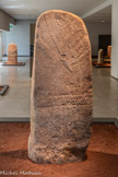 <center>Le musée Fenaille </center>Les statues-menhirs. Les figures sont représentées en pied, les jambes droites, la taille marquée par une ceinture. Les bras repliés sur le buste sont prolongés dans le dos par des épaules en forme de crosse. Les traits du visage sont simplifiés : seuls les yeux et le nez sont tracés, ainsi que des tatouages en forme de traits parallèles sur les joues ; il est très rare que la bouche soit dessinée. Souvent, les figures sont vêtues d’un grand manteau aux lourds plis parallèles. Vers 3 300 - 2 200 avant notre ère, grès. Calmels-et-Le-Viala