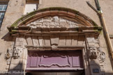 <center>Rue de l’Embergue </center>Hôtel Séguret. Les deux pilastres sont agrémentés d’un mascaron grotesque auquel est juxtaposée une moulure partiellement dégradée représentant un visage et un motif en spirale auquel est accroché un tissu. L’intérieur du fronton portait un décor sculpté presque entièrement disparu à cause de l’érosion. Le timbre au centre du bossage du linteau supportait probablement une pièce sculptée représentant les armes de la famille de Séguret. Cette pièce a vraisemblablement était buchée durant la Révolution.