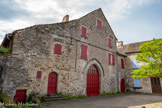 <center>Najac</center>Chapelle de saint Barthélémy. Cette chapelle, dont subsiste le portail d’entrée, était autrefois associée à un hôpital et à un cimetière. Elle relevait de la Dômerie d’Aubrac. Le corps de bâtiment qui longe le flanc est de la chapelle possède un étage de soubassement auquel on accède depuis la place par une porte semi-enterrée à linteau droit sur coussinets. Etablis sur deux assises, les coussinets sont ornés d'une moulure en quart-de-rond dégagée par un listel qui délimite un ove sur le profil. Une porte à arc segmentaire dotée d'un chanfrein amorti en congés biais ouvre sur le rez-de-chaussée légèrement surélevé. Une fenêtre à arc segmentaire éclaire l'étage unique La porte du bâtiment ouest (à droiye)  a un arc brisé aplati dont l'encadrement est mouluré d'un tore dégagé entre deux larges gorges.