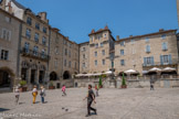 <center>Villefranche-de-Rouergue </center>La place est losangée. Les arcades se rejoignent aux angles en un étroit passage. La place est complétée par une croix en fonte dominée par la balustrade des couverts de Reyniès. En face, Maison Pomairols ou maison du Président Raynal, à côté à droite maison Breton. Cette maison, l'une des plus intéressantes de la place, comprend un rez-de-chaussée composé d'une boutique ouvrant sur les arcades, de deux étages avec des baies à linteau arrondi et, au quatrième étage, deux échauguettes carrées portées chacune sur quatre corbeaux. XVIIe siècle.