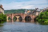 <center>Espalion</center>Le Pont-Vieux. Bien qu’il y ait un pont mentionné dans un acte de donation des seigneurs de Calmont en 1060, l’actuel pont, de style gothique construit en grès rouge, daterait probablement de la fin du XIIIe siècle. Bâti en « dos d’âne », à quatre arches sur des piles avec avant et arrière-becs triangulaires, en grès rose, date très probablement de la fin du XIIIe siècle. Les arches présentent en bordure trois arcades superposées (un triple rouleau) ; le rouleau supérieur, légèrement saillant, a permis d’élargir son tablier au XVIIIe siècle. Le Pont Vieux est uniquement piétonnier. Ce n’est qu’une fois les remparts de la ville démolis et l’ouverture du boulevard Joseph Poulenc que le Pont Neuf (qu'on aperçoit en arrière plan) , baptisé en 2013 « Pont des villes jumelles », a été construit et ouvert à la circulation en 1846.