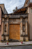 <center>Espalion</center>Ancien portail de l'Eglise du Couvent des Ursulines édifié au XVIIe siècle aujourd'hui détruit. La chapelle des Ursulines appartenait au couvent des Ursulines, situé sur la rive droite, à l’emplacement de l’actuel hôtel des postes. Sa construction débutée en 1656 ne fut achevée qu’en 1674. Lors de sa démolition en 1968, seules les pierres du grand portail ont été conservées et remontées en 2001, sur la rive gauche,
à l’entrée du foirail. Les quatre colonnes à chapiteaux corinthiens (décors constitués de deux rangées de feuilles d'acanthe) encadraient les niches des statues Sainte-Ursule et Saint-Augustin disparues au XXe siècle. Au-dessus du linteau, figure le blason sculpté des seigneurs de Calmont, fondateurs du couvent. Le fronton brisé encadrait une statue de la Vierge.