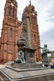 <center>Espalion</center>Église paroissiale Saint-Jean-Baptiste. Une jeune paysanne en bronze, rend hommage aux disparus et un lion serre une épée dans ses griffes. Il évoque les armoiries que s’est donnée la ville d’Espalion.