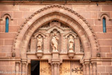 <center>Espalion</center>Église paroissiale Saint-Jean-Baptiste. Le portail central s'orne dans son tympan des statues du Bon Pasteur, de saint Jean-Baptiste et du patron de la cité, saint Hilarian.