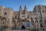 <center>Palais des Papes d'Avignon </center>La porte principale du palais des papes (porte  des Champeaux) est flanquée de deux tourelles dont les pyramides de couronnement sont décorées de crochets. La façade se compose d'une suite d'arcs percés de mâchicoulis à la hauteur de 15 mètres au-dessus du sol, et portant un chemin de ronde crénelé. A gauche, la tour d'angle. A droite, la tour de la Gache.