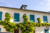 <center>Arcangues</center>La mairie. Les volets de la maison basque, pleins en bois à barre, sont peints de la même couleur que les autres pièces de bois des façades ou de la charpente. Ils sont en général d’un rouge assez foncé dit rouge basque. On trouve également, à partir du XIXe siècle un bleu très foncé, sorte de bleu de Prusse, ou un vert « profond » également foncé, et parfois un gris très clair. À Arcangues, le marquis Pierre d’Arcangues a introduit un bleu plus clair, qui a conservé la dénomination de bleu d'Arcangues.