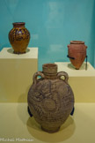 <center>Reflets du Nil</center>De droite a gauche :
Vase
Nagada II (3650-3350 av. notre ère)
Terre cuite peinte
LYON, MUSÉE DES CONFLUENCES.
Les anciens Égyptiens utilisaient des gobelets en terre cuite, rarement conservés, pour boire l’eau au quotidien. Les vases destinés au stockage nous sont en revanche parvenus. Des décors figurés ou géométriques à caractère nilotiques y étaient représentés.
Ce vase prédynastique présente un décor rouge caractéristique de la période Nagada. Les lignes ondulées parcourant la panse de l'objet correspondent à la forme pré-épigraphique du signe hiéroglyphique de l'eau, représenté comme une vaguelette. <br>
Gargoulette
Époque byzantine - début époque islamique (600-800)
Terre cuite peinte
PARIS, MUSÉE DU LOUVRE.
Les gargoulettes permettent de conserver la fraîcheur de l'eau tout en décorant la table. Cette gargoulette byzantine, modelée et tournée en terre jaunâtre recouverte d’un engobe blanc, présente des décors aux traits bruns. Des motifs de poissons et de végétations ornent la panse du vase. Des spirales et hachures évoquent les vibrations de l’eau et la fonction du récipient. <br>
Vase à décor épigraphique
14e siècle
Céramique
PARIS, MUSÉE DU LOUVRE.