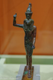 <center>Reflets du Nil</center>Statuette du dieu Horus harponneur Basse Époque (664-332 av. notre ère)
Bronze
GENÈVE, FONDATION GANDUR POUR L’ART. <br>
Lors d’un combat mythique pour la royauté entre Horus et Seth, ce dieu du désordre se transforma en hippopotame et fut harponné. Horus est ici dans la position d’un chasseur tenant dans la main droite un harpon et dans la gauche une corde reliée à la pointe amovible, qui en se détachant du manche transpercera le cuir de l’animal. Il incarne le souverain anéantissant les forces du mal et garantissant Maât, l’ordre cosmique et social. Dans un contexte funéraire, royal ou privé, les représentations de harponnage détruisent magiquement les ennemis susceptibles de nuire au défunt.