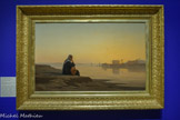 <center>Reflets du Nil</center>Louis-Auguste Veillon (Bex, 1834 - Genève, 1890)
Le Nil près de Philae
1869
Huile sur toile
GENÈVE, MAH MUSÉE D’ART ET D’HISTOIRE, LEGS GUSTAVE REVILLIOD, 1890. <br>
Louis-Auguste Veillon, originaire de Suisse, se rend à plusieurs reprises en Égypte en 1873 et 1885. Il peint plusieurs paysages figurant le Nil dans des tons jaune orangé, imprégnés d’une atmosphère onirique. Le tableau témoigne du point de vue européen. Il reflète l’apaisement et l’émerveillement lié à l’observation du Nil. La présence d’une Égyptienne regardant le fleuve, motif oriental classique, nous invite à la contemplation, sans pour autant tomber dans un exotisme caricatural.