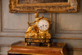 <center>Grand cabinet </center>Pendule : La Prudence ou Cléopâtre. 1780.  Pendule en bronze doré représentant, sur une base en ébène, une femme assise, appuyée sur le cadran, tenant un serpent et se regardant dans un miroir. La base repose sur quatre pieds en bronze doré. Elle est ornée en façade d'une frise de postes en bronze doré. Un deuxième niveau de base accueille un masque féminin des cheveux de laquelle partent deux guirlandes se raccrochant sur les bords au coeur de deux rosettes.