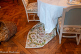 <center>La Salle à manger </center>Tapis de table rectangulaire en soie brodé d'un décor végétal réalisé au fil de soie multicolore et en fils métalliques dorés. Le décor est symétrique selon un axe vertical. Un médaillon central est formé autour d'un motif de coeur encadré d'un oiseau de chaque côté et de rinceaux de branches fleuries et de fruit. La bordure richement brodée selon le même thème est symétrique selon un axe horizontal. Le fond du tapis est un taffetas de soie de teinte beige clair, formé de 6 lés et doublé d'une toile de lin écrue qui soutient les broderie en soie et fils métalliques. 18e siècle
