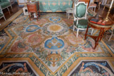 <center>Chambre d'apparat de Mme Thierry de Ville d'Avray.</center>Tapis de sol. Manufacture de la Savonnerie. 1668-1699. Dans un cadre godronné, dont les angles sont marqués par des médaillons ovales imitant des camées, prennent place des motifs de rinceaux multicolores sur un fond sombre. Aux extrémités, deux grands médaillons ovales, cernés de godrons dorés, sont occupés par des trophées militaires sur un fond bleu. Ils encadrent un caisson central accompagné de volutes et de rinceaux. Au centre sont disposés les armes de France et de Navarre autour d'un soleil. Ce tapis, réalisé par la manufacture de la Savonnerie d'après les dessins de Charles Le Brun, fait partie des 93 tapis commandés en 1668 pour orner les 425 mètres de plancher de la Grande Galerie du Louvre.