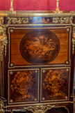 <center>Cabinet doré.</center>Un trophée musical orne l'abattant tandis que les panneaux inférieurs représentent des vases garnis de fleurs et de fruits.