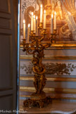 <center>Salon des Amiraux.</center>Paire de candélabres en bronze ciselé et doré représentant un putto tenant une corne d'abondance de laquelle s'échappent huit bras de lumière. Il prend place sur une base de rochers soutenue par quatre pieds en rinceaux feuillagés. Le putto, en contrapposto, porte une cape nouée autour de son cou et regarde vers le bas tout en maintenant d'une main la base végétale de la corne d'abondance et levant l'autre bras à hauteur des fruits qui en sortent. Les bras de lumière prennent la forme de branches feuillues tortueuses, se terminant par un bouton de rose. Ces créations du Second Empire s'inspirent des formes du style Louis XV. 1850-1874.
