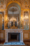 <center>Salon d'honneur.</center>Paire de chandeliers en bronze doré et patiné sur base tripode, à pattes de lion portant un tronc de pyramide à fond noir orné de candélabres surmontés d’une figure féminine à l’antique. La partie supérieure se compose de sept bras de lumière supportés par des figures de griffons.