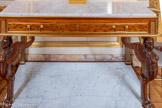 <center>Galerie dorée</center>Paire de consoles rectangulaires plaquées d’acajou moucheté, reposant sur une plinthe formant tablette en marbre blanc. Les pieds antérieurs sont sculptés d’un protome de sphinge sur patte de lion en acajou et les pieds postérieurs en forme de pilastres cannelés. La ceinture, marquée aux angles par un motif de table en laiton doré, accueille un tiroir à deux prises. Le tout est couvert d’un plateau de marbre blanc. 1847-1900
La maison Jeanselme (ou Janselme) est une importante entreprise d’ébénisterie parisienne du XIXe siècle qui émerge dans le contexte des Expositions des Produits de l’Industrie. Elle rachète le fond d’atelier de la dynastie Jacob en 1847. La maison se spécialise dans la réalisation de meubles dans le goût historiciste, prisés sous la Monarchie de Juillet et le Second Empire. Elle compte parmi les fournisseurs importants du garde-meuble impérial et se distingue lors de nombreuses Expositions Universelles, comme en 1855.
Ici, ces consoles de style Empire reprennent les modèles du premier quart du XIXe siècle établis par Percier et Fontaine et mis en œuvre par Jacob-Desmalter ou Marcion.