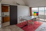 <center>Immeuble Le Corbusier</center>La salle à manger est largement ouverte sur Boulogne, par une grande baie vitrée
modifiée à plusieurs reprises et par un balcon loggia. Le vitrail coloré, de forme
géométrique, a été créé à Reims par l’artiste Brigitte Simon et ajouté en 1949. Un
tapis de haute laine rouge, tissé à Tlemcen en Algérie, fait ressortir la table en marbre dessinée par Le Corbusier et entourée de quatre fauteuils -bistrot Thonet (1859). d’un plateau
rectangulaire en marbre. Elle repose sur deux pieds en forme de « trompette ».